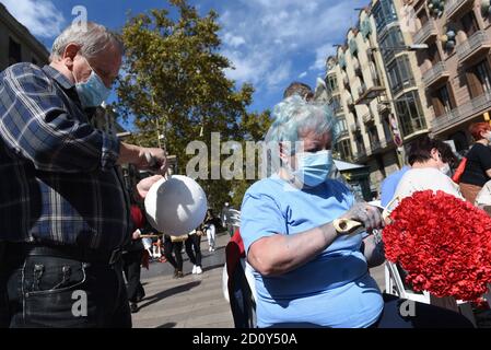 Barcelona, Spanien. Oktober 2020. Ein Mann trägt eine Gesichtsmask hilft, einen Blumenstrauß während der Feier des Roser de La Rambla Festival vorzubereiten.Roser Festival wird jedes Jahr ohne weiteres seit 1962 statt. Nachbarn dieses Viertels im Zentrum von Barcelona schmücken Straßen und Gebäude mit Blumen zu Ehren der Jungfrau vom Rosenkranz, schutzpatronin der berühmten Straße La Rambla. Kredit: SOPA Images Limited/Alamy Live Nachrichten Stockfoto