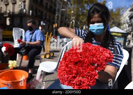 Barcelona, Spanien. Oktober 2020. Eine Frau, die eine Gesichtsmask trägt, bereitet während der Feier des Festivals Roser de La Rambla einen Blumenstrauß vor.das Festival Roser findet seit 1962 jedes Jahr ohne weiteres statt. Nachbarn dieses Viertels im Zentrum von Barcelona schmücken Straßen und Gebäude mit Blumen zu Ehren der Jungfrau vom Rosenkranz, schutzpatronin der berühmten Straße La Rambla. Kredit: SOPA Images Limited/Alamy Live Nachrichten Stockfoto