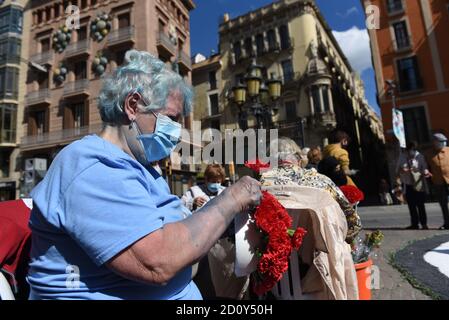 Barcelona, Spanien. Oktober 2020. Eine Frau, die eine Gesichtsmask trägt, bereitet während der Feier des Festivals Roser de La Rambla einen Blumenstrauß vor.das Festival Roser findet seit 1962 jedes Jahr ohne weiteres statt. Nachbarn dieses Viertels im Zentrum von Barcelona schmücken Straßen und Gebäude mit Blumen zu Ehren der Jungfrau vom Rosenkranz, schutzpatronin der berühmten Straße La Rambla. Kredit: SOPA Images Limited/Alamy Live Nachrichten Stockfoto