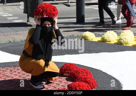 Barcelona, Spanien. Oktober 2020. Eine Frau mit Gesichtsmast posiert für ein Bild mit einem Blumenstrauß auf dem Kopf während der Feier des Festivals Roser de La Rambla.das Roser Festival findet seit 1962 jedes Jahr statt. Nachbarn dieses Viertels im Zentrum von Barcelona schmücken Straßen und Gebäude mit Blumen zu Ehren der Jungfrau vom Rosenkranz, schutzpatronin der berühmten Straße La Rambla. Kredit: SOPA Images Limited/Alamy Live Nachrichten Stockfoto