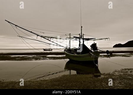 Sepia Silhouette eines festgemachtes Fischerboot zeigt ein reflektiertes Bild und enge Detail der Takelage. Stockfoto