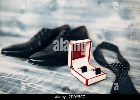 Schwarze Leder Herrenschuhe mit Box Manschettenknöpfe und Polka Dot Krawatte auf Holz Textur mit geringer Schärfentiefe. Stockfoto