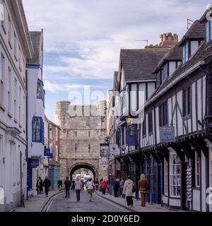 Bootham Bar, York. Ein altes Tor zur Stadt, das am Ende einer Straße steht. Geschäfte sind auf jeder Seite und der Verkehr ist durch den Bogen sichtbar. Stockfoto