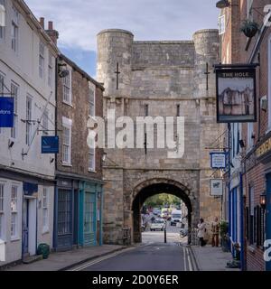 Bootham Bar, York. Ein altes Tor zur Stadt, das am Ende einer Straße steht. Geschäfte sind auf jeder Seite und der Verkehr ist durch den Bogen sichtbar. Stockfoto