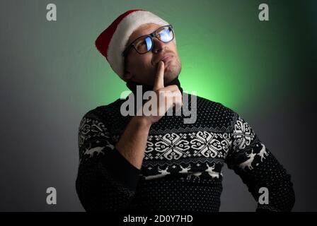 Ein junger Mann mit Brille und Weihnachtsmütze dachte darüber nach, Stockfoto
