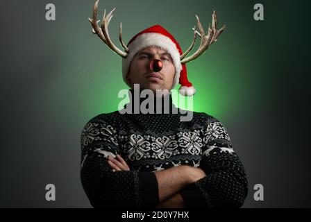 Ein Mann im Bild eines Weihnachtshirsches mit Hörnern und einer roten Nase, Stockfoto