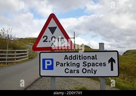 Zwei Meter Höhenbegrenzung mit verschwommener Barriere im Hintergrund. Schild für zusätzliche Parkplätze Autos nur mit Pfeil und Parkplatz Symbol. VEREINIGTES KÖNIGREICH. Stockfoto