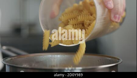 Nahaufnahme von Fusilli, die in einen Topf mit kochendem Wasser fallen, breites Foto Stockfoto