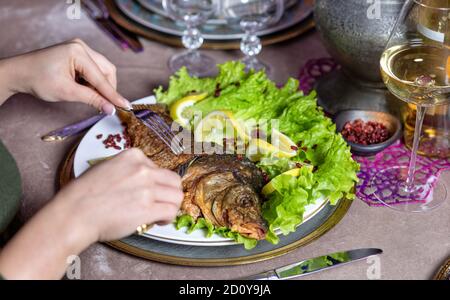 Frau essen einen gegrillten ganzen Fisch mit einer Zitrone Stockfoto
