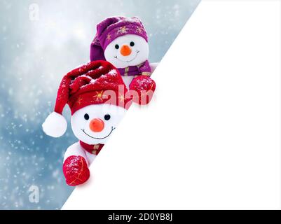 Zwei kleine Schneemänner das Mädchen und der Junge in Mützen und Schals auf Schnee im Winter. Festliche Hintergrund mit einem lustigen Schneemann. Weihnachtskarte, kopieren. Stockfoto