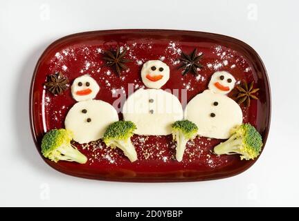 Lustiger Teller mit drei Schneemännern aus Mozzarella und Brokkoli. Frühstücksidee für Kinder. Vegetarisches Essen für Neujahr oder Weihnachtsfeier. Stockfoto