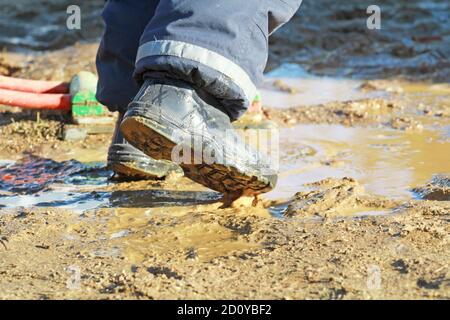 Junge mit Gummistiefeln in einer Pfütze Stockfoto