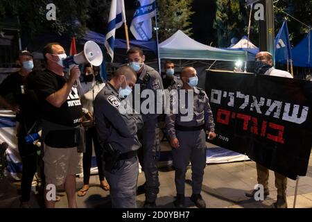 JERUSALEM, ISRAEL - OKTOBER 03: Die israelische Polizei steht zwischen einem pro-Netanjahu-Gegen-Demonstranten, der ein Banner mit der Aufschrift "Linke sind Verräter" hält, und einem Anti-Netanjahu-Demonstranten, der während einer Demonstration vor dem offiziellen Wohnsitz des Premierministers ein Bullhorn benutzt, trotz einer landesweiten Sperre, die darauf abzielt, die Coronavirus-Pandemie am 03. Oktober 2020 in Jerusalem, Israel, einzudämmen. Das israelische parlament hat letzte Woche ein Gesetz verabschiedet, das Demonstrationen als Teil eines mit dem Coronavirus in Verbindung stehenden Ausnahmezustands einschränkt. Kritiker sagen, dass es darauf abzielt, Proteste gegen Netanjahu zum Schweigen zu bringen Stockfoto