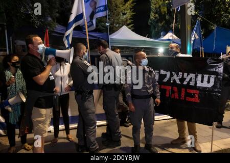 JERUSALEM, ISRAEL - OKTOBER 03: Die israelische Polizei steht zwischen einem Pro-Netanjahu-Gegenprotester mit einem Banner, auf dem "Linke sind Verräter" steht, und einem Anhänger der Anti-Netanjahu-Bewegung der schwarzen Flagge, der während einer Demonstration vor dem offiziellen Sitz des Premierministers trotz einer landesweiten Abriegelung zur Eindämmung der Coronavirus-Pandemie am 03. Oktober ein Megafon benutzt; 2020 in Jerusalem, Israel. Das israelische parlament hat letzte Woche ein Gesetz verabschiedet, das Demonstrationen im Rahmen eines durch das Coronavirus bedingten Ausnahmezustands einschränkt, der laut Kritikern darauf abzielt, Proteste gegen Netanjahu zum Schweigen zu bringen Stockfoto