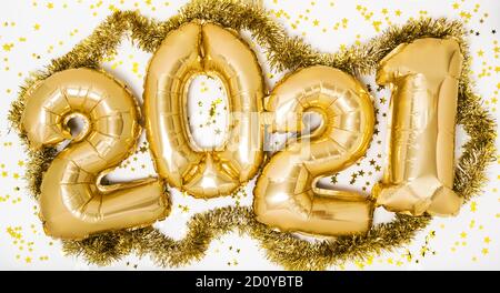 Goldene 2021 Luftballons. Gold metallic Folie Zahlen für Happy New Year Feier auf weißem Hintergrund mit Glitzer Konfetti Sterne. Heliumballon als Hol Stockfoto