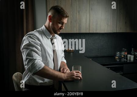 Schöner Mann in Anzug, trinken Whiskey in der Küche zu Hause Stockfoto