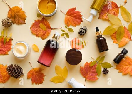 Herbst Hautpflegeprodukte und Herbstblätter auf gelbem Grund, flach liegend, Kopierfläche. Saisonale Beauty-Routine und Bio-Kosmetik-Konzept. Stockfoto