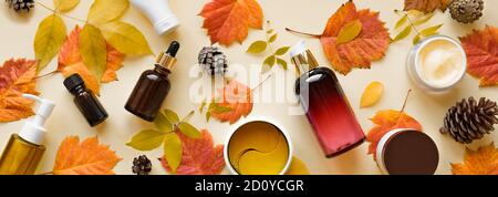 Herbst Hautpflegeprodukte und Herbstblätter auf gelbem Grund, flach liegend, Kopierfläche. Saisonale Beauty-Routine und Bio-Hautpflege-Konzept. Stockfoto