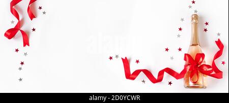 Champagnerflasche mit roter Schleife und Sternen isoliert auf weißem Hintergrund. Campagne für Weihnachten oder Geburtstag, Draufsicht, Kopierbereich. Stockfoto