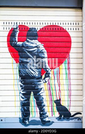 Rom, Italien. Der heruntergezogene Shop-Shutter zeigt einen Künstler, der ein Herz an die Wand sprüht, während eine schwarze Katze sitzt und watches.in im Banksy-Stil Stockfoto