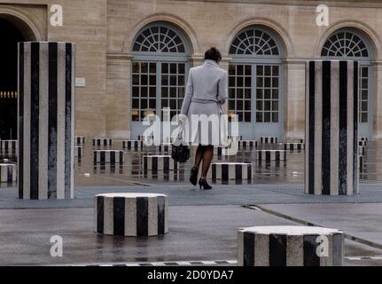 ELEGANTE FRAU, DIE AN DANIEL BUREN SÄULEN IM PALAIS ROYAL VORBEIKOMMT PARIS WÄHREND DER KALTEN JAHRESZEIT - PARIS FRANKREICH - PARIS KUNST - PARIS FRAU - PARIS FARBE STRASSENFOTOGRAFIE © Frederic BEAUMONT Stockfoto