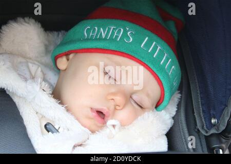 Baby schläft im Kinderwagen trägt Hut sagen Santa kleinen Helfer Stockfoto