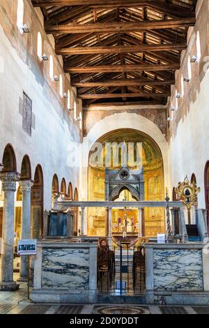 Das Kirchenschiff der Kirche Santa Maria in Cosmedin, Rom. Holzsparren und Dach, eine Reihe von kleinen gewölbten Fenstern unten, und Säulen, und der Altar. Stockfoto