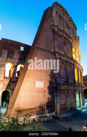 Abschnitt des beleuchteten römischen Kolosseums in Rom während der blauen Stunde am frühen Abend. Die Inneneinrichtung wird durch gelbe Beleuchtung beleuchtet. Stockfoto