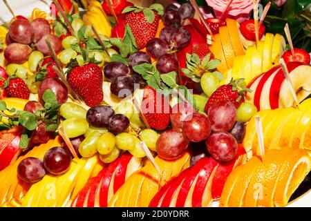 Authentisches Buffet mit verschiedenen frischen Früchten, Beeren und Zitrusfrüchten. Stimmungsvolle Morgenbeleuchtung, modischer, trendiger Spot-Weichfokus. Stockfoto