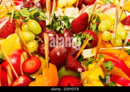 Authentisches Buffet mit verschiedenen frischen Früchten, Beeren und Zitrusfrüchten. Stimmungsvolle Morgenbeleuchtung, modischer, trendiger Spot-Weichfokus. Stockfoto