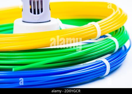 Nahaufnahme der Reihe von bunten gerollten Kabel um Kinder 3D-Druckstift isoliert auf weiß. Drei helle Filament Kunststoff liegen drinnen. Konz Stockfoto