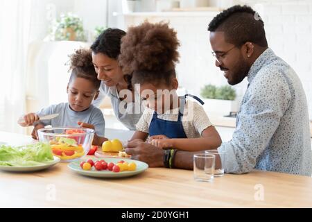 Glücklich gemischte Rennen junge Eltern lehren kleine Kinder Kochen. Stockfoto