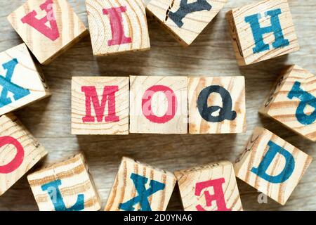 Buchstabenblock im Wort MOQ (Abkürzung für Mindestbestellmenge) mit einem anderen auf Holzhintergrund Stockfoto