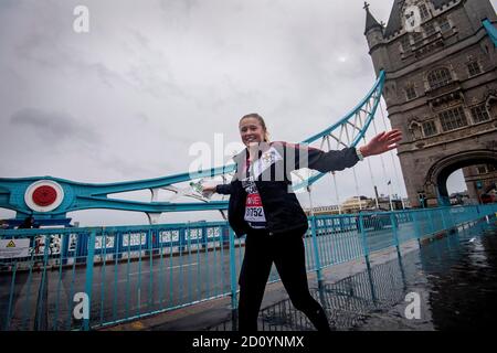 Ein Läufer mit einer London-Marathon-Laufnummer überquert die Tower Bridge, während etwa 45,000 Menschen den 40. London Marathon auf ihrer eigenen 26.2-Meilen-Strecke durch Großbritannien laufen oder laufen, nachdem das ursprünglich für April 26 geplante Ereignis aufgrund eines Coronavirus verschoben wurde. Stockfoto