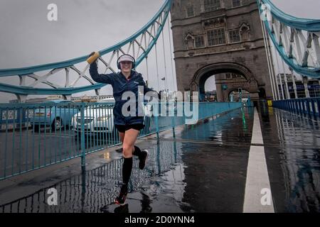 Ein Läufer mit einer London-Marathon-Laufnummer überquert die Tower Bridge, während etwa 45,000 Menschen den 40. London Marathon auf ihrer eigenen 26.2-Meilen-Strecke durch Großbritannien laufen oder laufen, nachdem das ursprünglich für April 26 geplante Ereignis aufgrund eines Coronavirus verschoben wurde. Stockfoto