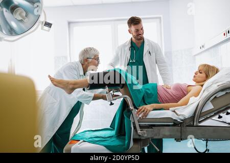 In dem Krankenhaus treibt die Frau in der Arbeit die Geburt voran, Geburtshelfer helfen Stockfoto