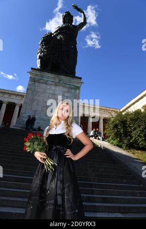 München, Deutschland. Oktober 2020. Das Münchner Kindl Viktoria Ostler steht in einem schwarzen Gedenkdirndl zur abgesagten Wiesn 2020 der Trachtenmanufaktur Amsel Trachten mit einem Strauß roter Rosen auf den Stufen vor dem Bayern auf der Theresienwiese. Quelle: Felix Hörhager/dpa/Alamy Live News Stockfoto