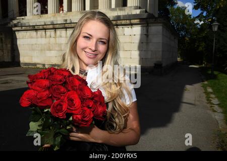 München, Deutschland. Oktober 2020. Die Münchner Kindl Viktoria Ostler steht in einem schwarzen Gedenkdirndl für die abgesagte Wiesn 2020 der Trachtenmanufaktur Amsel Trachten mit einem Strauß roter Rosen auf der Bayern nahe der Theresienwiese. Quelle: Felix Hörhager/dpa/Alamy Live News Stockfoto