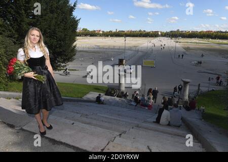 München, Deutschland. Oktober 2020. Das Münchner Kind Viktoria Ostler steht in einem schwarzen Gedenkdirndl für die abgesagte Wiesn 2020 mit einem Strauß roter Rosen auf den Stufen vor dem Bayern an der Theresienwiese. Quelle: Felix Hörhager/dpa/Alamy Live News Stockfoto