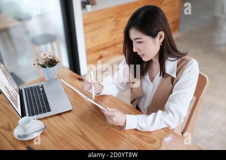 Lächelnde Frau, die mit einem Tablet-Computer arbeitet, über dem Foto. Stockfoto