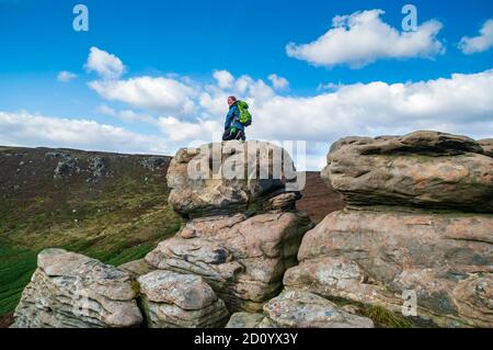 Dominika Wroblewska auf einem großen windzerodierten Felsbrocken am Rande des beringten Roger-Ausbisses auf Kinder Scout. Stockfoto