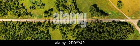 Luftaufnahme auf Eisenbahn im Bau, zwischen Wäldern, Feldern und Dörfern. Straßenarbeiten im Wald und auf Feldern. Unbefestigte Straße in einem offenen Bereich Stockfoto