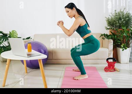 Asiatische Frau tut Kniebeugen Stockfoto