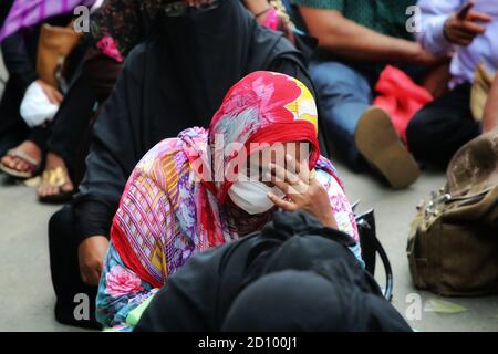 Dhaka, Bangladesch. Oktober 2020. Eine Arbeitsmigrantin, die eine Maske trägt, sieht sich ausruhen, als sie vor dem Büro von Saudia Arabian Airlines in Bangladesch auf ihr Rückflugticket zu ihren Arbeitsplätzen wartet.Arbeiter aus Bangladesch, die nach Saudi-Arabien zurückkehren wollten, um wieder an ihre Arbeit zu kommen, mussten Stunden warten, bevor sie ihre einholten Der Flug als Flughafen erforderte nur eine kleine Anzahl von Menschen, um nach innen zu gelangen, um die Coronavirus-Pandemie zu bekämpfen. Kredit: SOPA Images Limited/Alamy Live Nachrichten Stockfoto