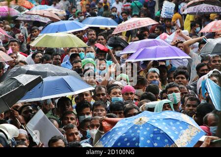 Dhaka, Bangladesch. Oktober 2020. Bangladeschische Wanderarbeiter, die in Saudi-Arabien arbeiten, tragen Regenschirme, um sie vor der Hitze zu schützen, um Rückflüge zu ihren Arbeitsplätzen in Saudi-Arabien zu sammeln.bangladeschische Arbeiter, die nach Saudi-Arabien zurückkehren wollten, um wieder an ihre Arbeit zurückzukehren, mussten Stunden warten, bevor sie ihre einholten Der Flug als Flughafen erforderte nur eine kleine Anzahl von Menschen, um nach innen zu gelangen, um die Coronavirus-Pandemie zu bekämpfen. Kredit: SOPA Images Limited/Alamy Live Nachrichten Stockfoto