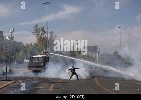 Santiago, Chile. Oktober 2020. Demonstranten geben Tränengasgranaten zurück, die ihnen von der Bereitschaftspolizei während des Protestes geworfen wurden.Hunderte von Demonstranten konfrontieren die Polizei in der Nähe der Plaza Baquedano, die von den Menschen in "Plaza de la Dignidad" umbenannt wurde, um Gerechtigkeit für Antoni zu fordern, Eine 16-Jährige, die am vorigen Protesttag von der Polizei von einer Brücke geworfen wurde. Kredit: SOPA Images Limited/Alamy Live Nachrichten Stockfoto