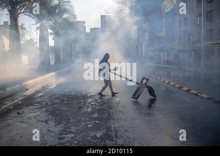 Santiago, Chile. Oktober 2020. Ein Protestler geht auf der Straße inmitten von bewölktem Tränengas während des Protestes mit der Bereitschaftspolizei in SantiagoHunderte von Demonstranten konfrontieren die Polizei in der Nähe der Plaza Baquedano, die von den Menschen in "Plaza de la Dignidad" umbenannt wurde, um Gerechtigkeit für Antoni zu fordern, Eine 16-Jährige, die am vorigen Protesttag von der Polizei von einer Brücke geworfen wurde. Kredit: SOPA Images Limited/Alamy Live Nachrichten Stockfoto