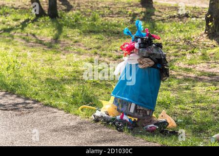 Übervolle Mülltonne im Park - Abfall, Plastiktüten, Hundekot, chaotisch Stockfoto
