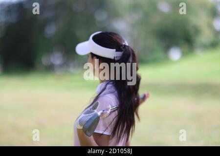 Frau halten Golfschläger in den Händen und schauen in die Ferne. Stockfoto