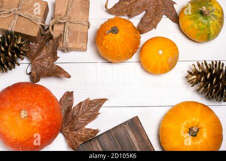 Kürbisse, Herbstblätter, goldene Tannenzapfen und handgefertigte Bastelgeschenke auf weißem Holzhintergrund. Holliday Dekoration Konzept Design. Stockfoto